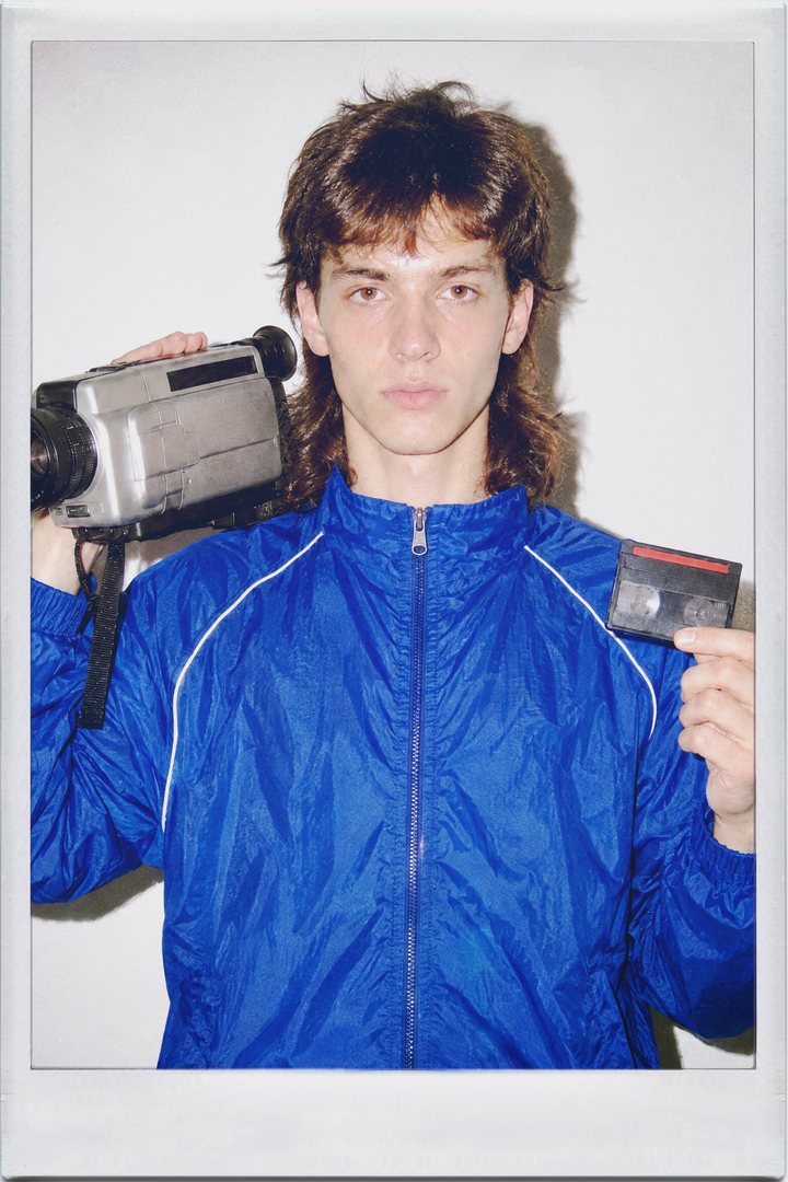 Cinamatic, front: a young man holding a camcorder and a tape