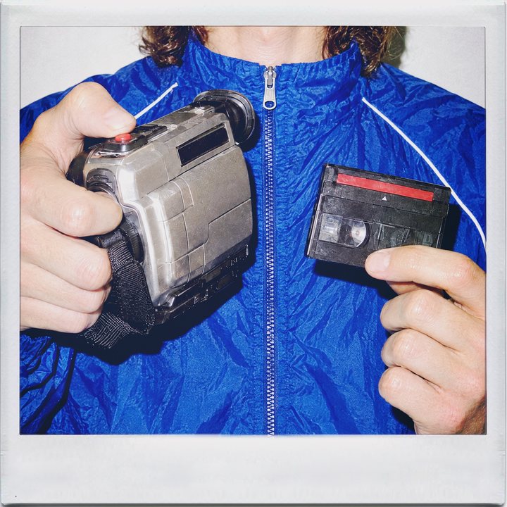 Cinamatic, hands: a young man holding a camcorder and a tape