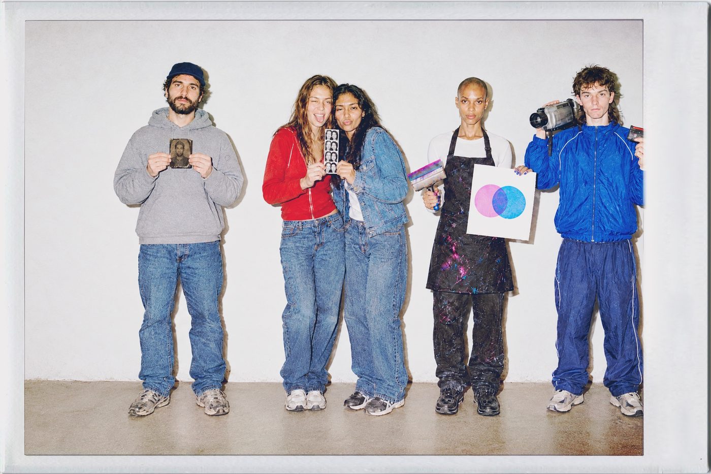 The Winter 26/27 lineup against a white wall: TinType&rsquo;s sitter with his plate, IncrediBooth&rsquo;s two friends with their strip, SwankoLab&rsquo;s printer with her print and Cinamatic&rsquo;s skater with his camcorder